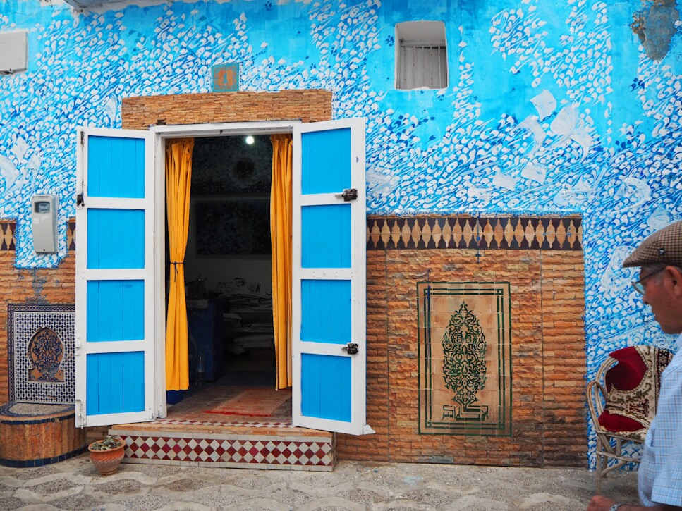 Fachada turquesa de loja tradicional na Medina de Assilah, Marrocos, com portais coloridos e arquitetura histórica