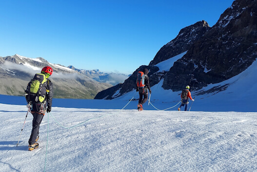 Aventureiros a caminhar numa montanha coberta de neve com equipamento de inverno